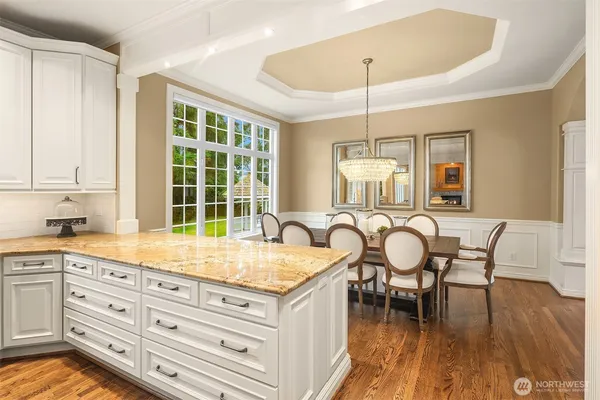 a kitchen with granite countertop a table chairs stove and wooden floors