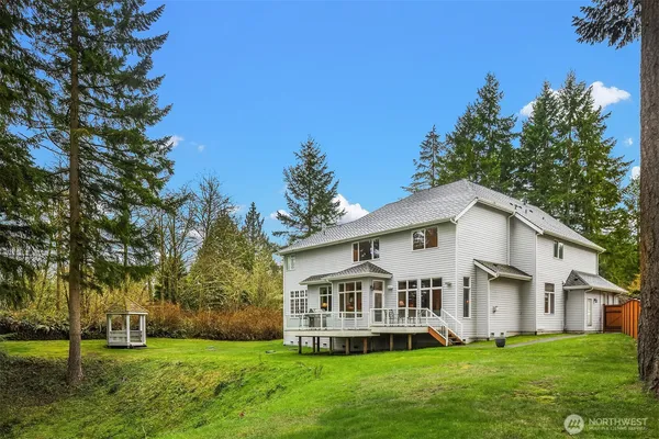 a view of a house with a big yard and large trees