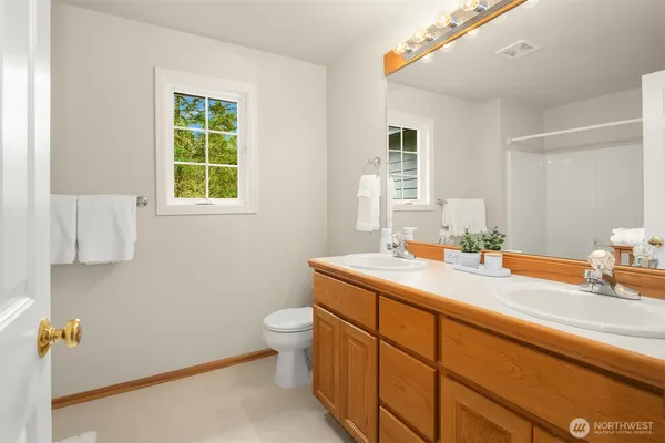a en suite bathroom with a granite countertop sink a toilet and a mirror
