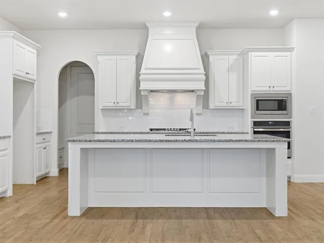 a kitchen with granite countertop a white stove top oven sink and wooden floor