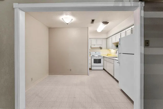 a view of a kitchen with white cabinets and refrigerator