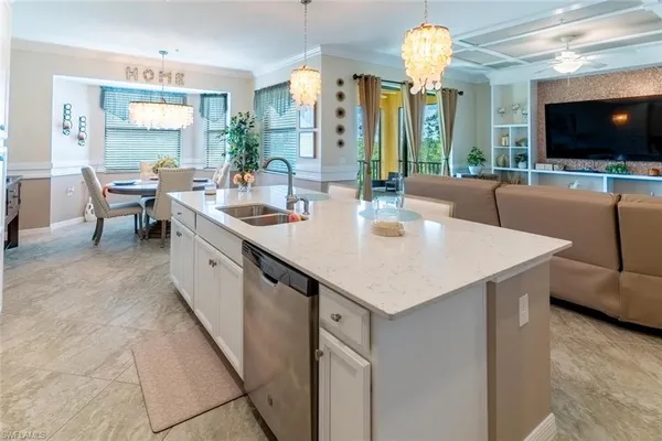 a kitchen with a sink a counter top space and living room view