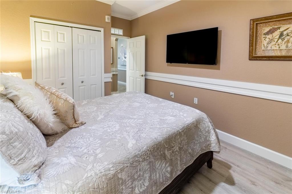 9596 Trevi Court, Unit 5446 Naples, FL 34113 - Photo 19 of 50 a bedroom with a bed and a flat screen tv