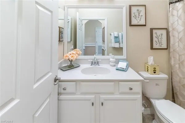 a bathroom with a granite countertop toilet sink and mirror