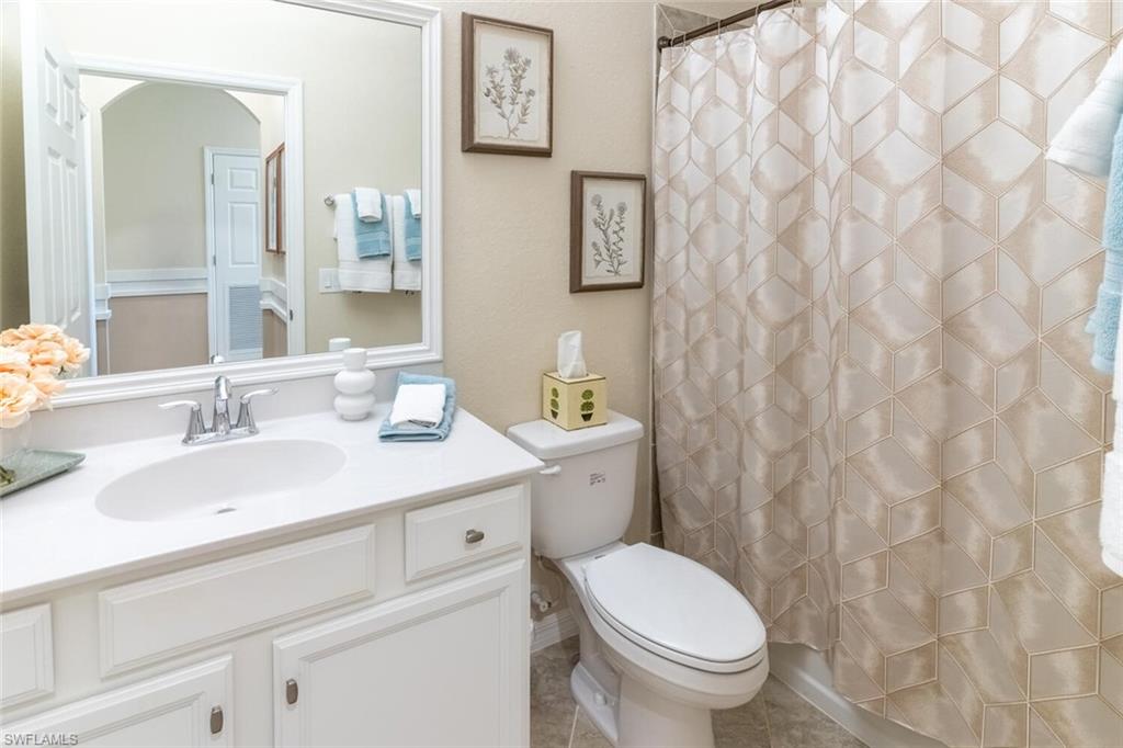 9596 Trevi Court, Unit 5446 Naples, FL 34113 - Photo 21 of 50 a bathroom with a granite countertop toilet sink and mirror