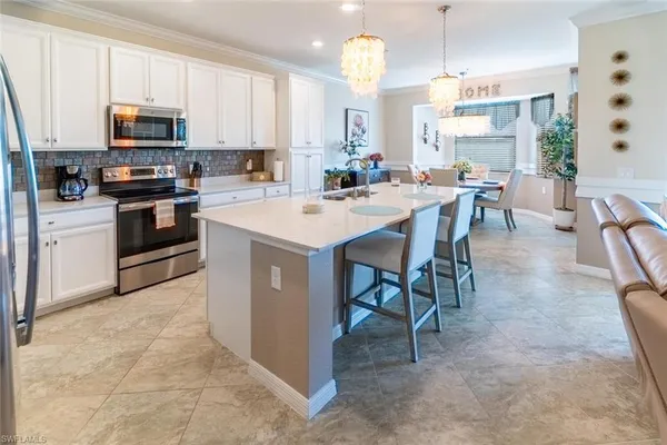 a kitchen with stainless steel appliances a table chairs sink and cabinets