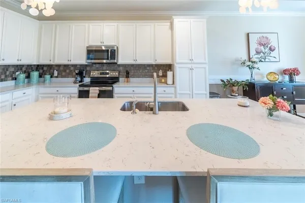 a kitchen with kitchen island a sink a stove and white cabinets
