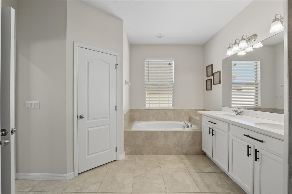 12154 Beach Fern Road Orlando, FL 32824 - Photo 20 of 34 a spacious bathroom with a tub sink and mirror