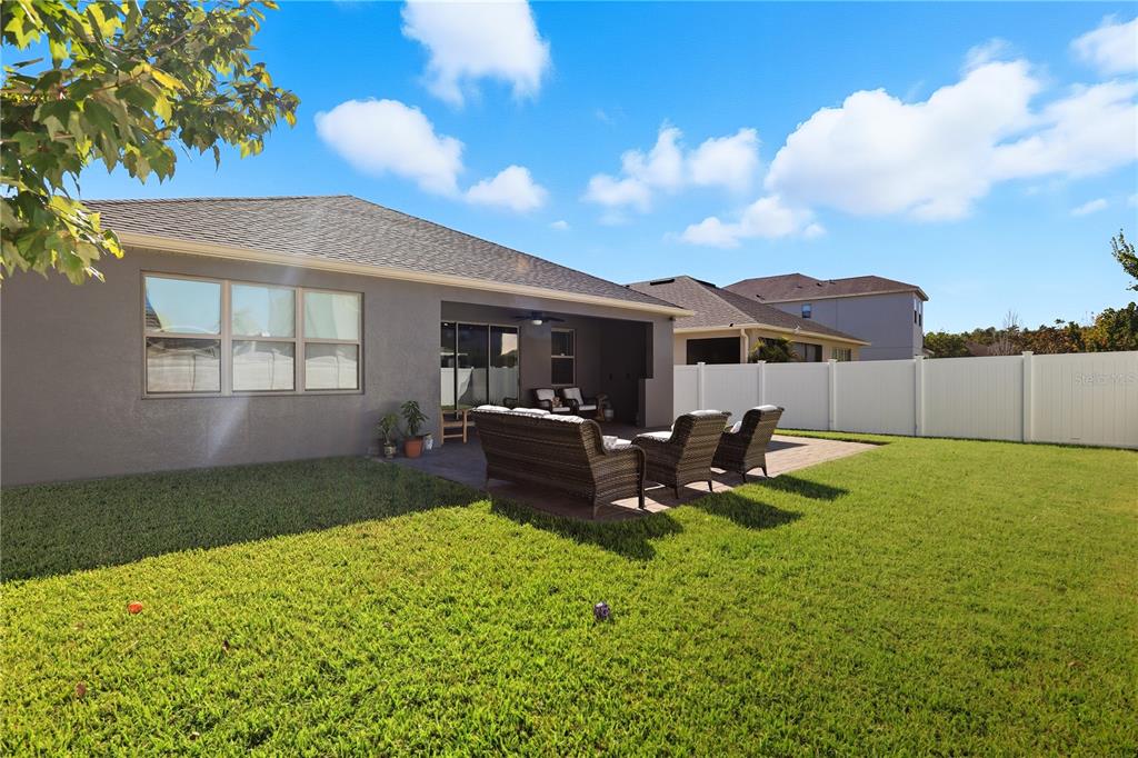 12154 Beach Fern Road Orlando, FL 32824 - Photo 28 of 34 a view of a backyard with table and chairs under an umbrella with wooden fence