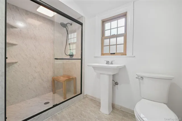a bathroom with a shower sink mirror and toilet