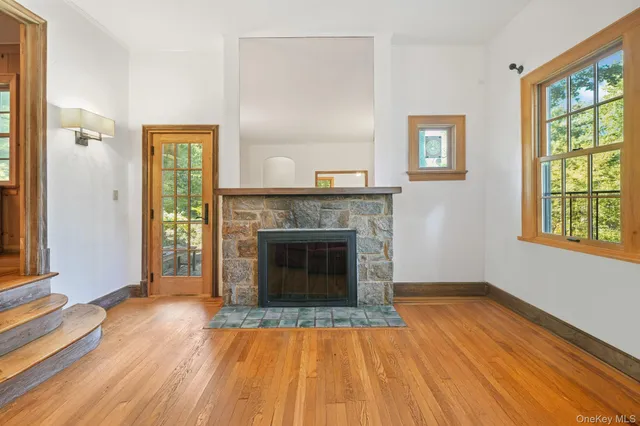 a view of an empty room with wooden floor fireplace and a window