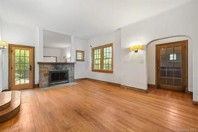 an empty room with wooden floor fireplace and windows