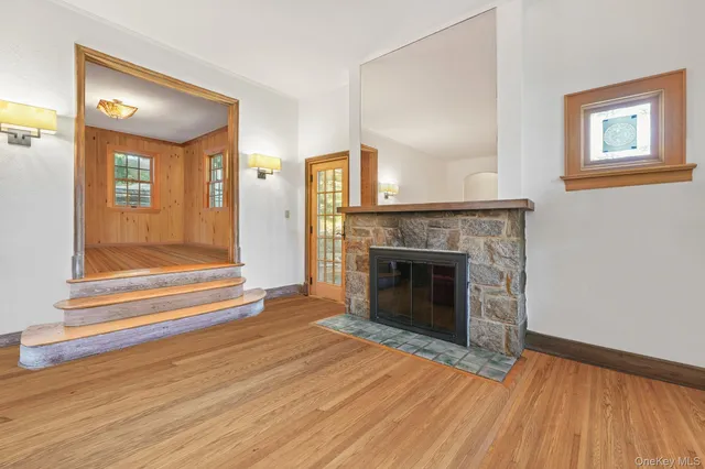 a view of an empty room with wooden floor fireplace and a window