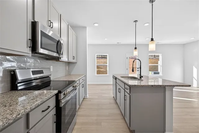 a kitchen with stainless steel appliances granite countertop a sink a stove and a wooden floor