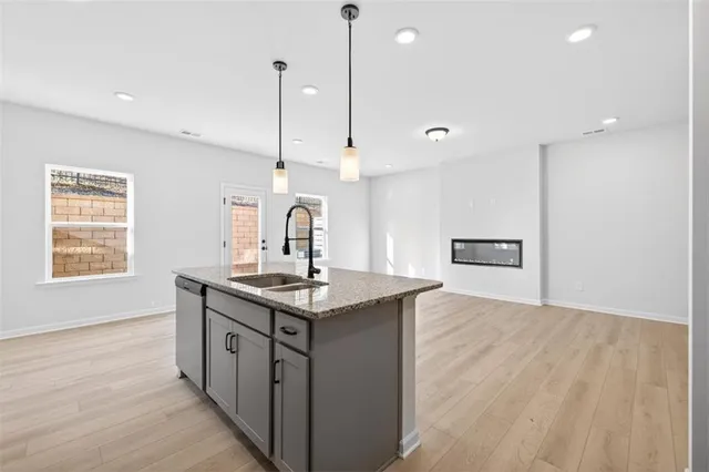 a kitchen with stainless steel appliances granite countertop a sink a stove and a wooden floor