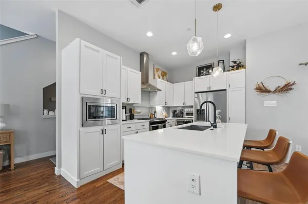 a kitchen with kitchen island a white counter top space cabinets and stainless steel appliances