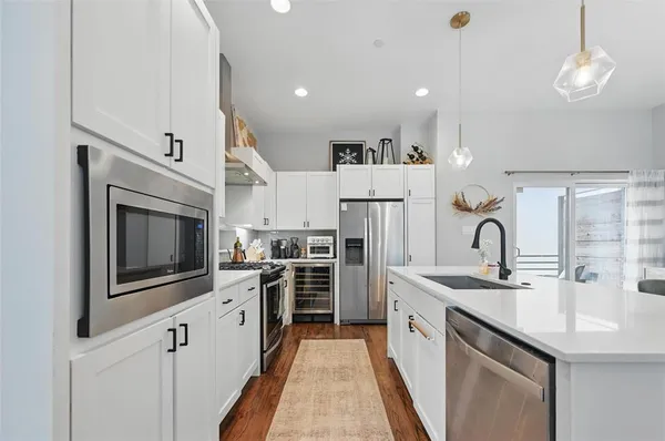 a kitchen with refrigerator a sink and wooden floor