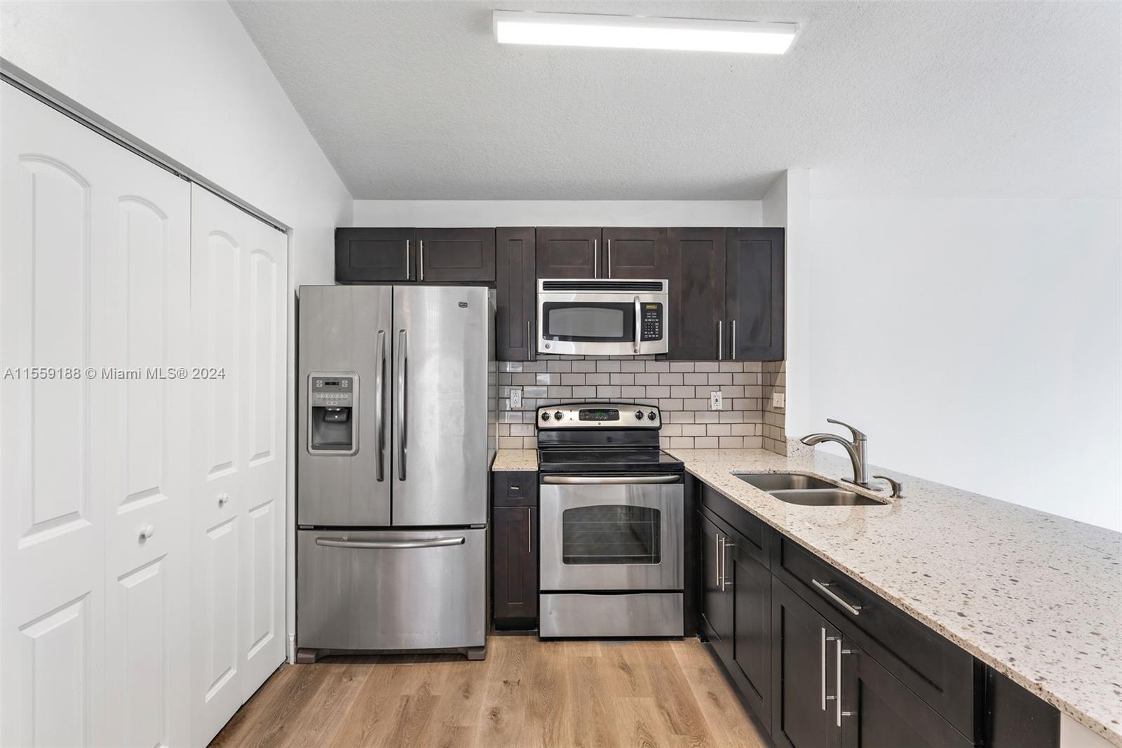 17767 Southwest 144th Avenue Miami, FL 33177 - Photo 4 of 21 a kitchen with stainless steel appliances a refrigerator a sink and wooden floors