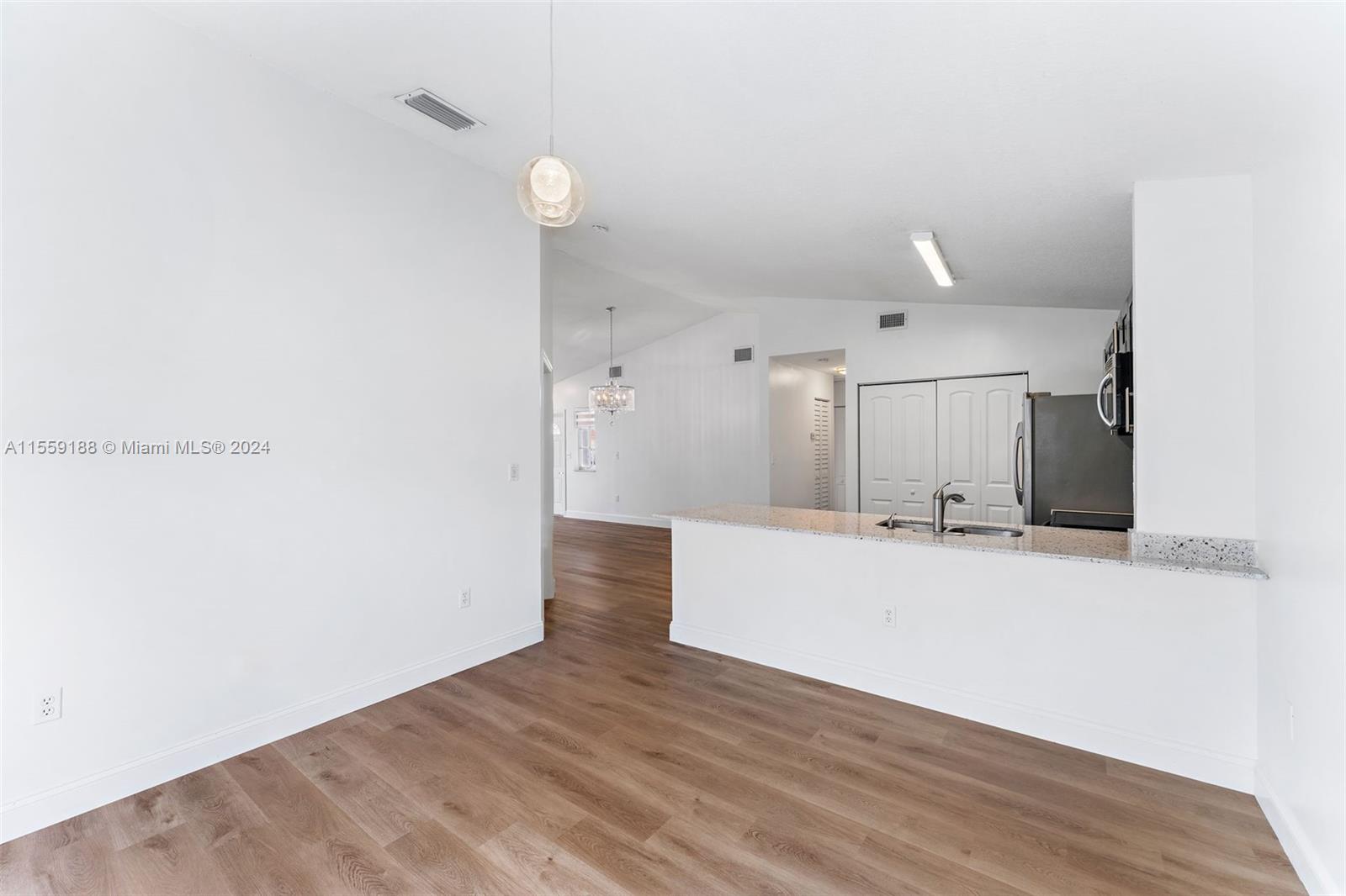 17767 Southwest 144th Avenue Miami, FL 33177 - Photo 8 of 21 a view of a kitchen with kitchen island a sink wooden floor and a large window