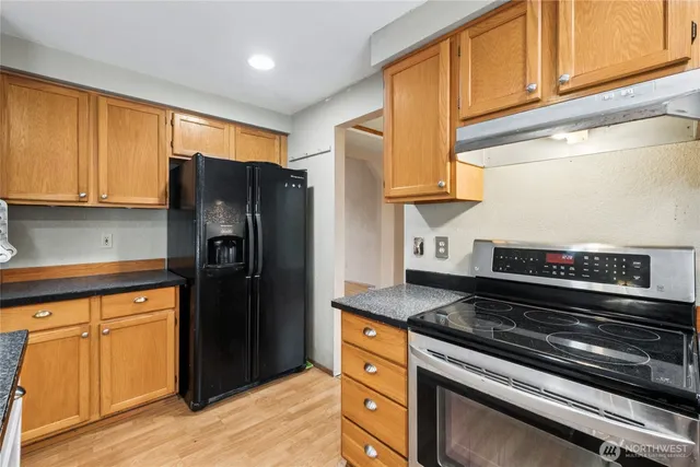 a kitchen with stainless steel appliances granite countertop a refrigerator and a stove top oven