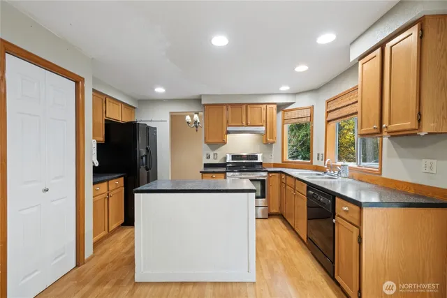 a kitchen with stainless steel appliances granite countertop refrigerator sink and wooden cabinets