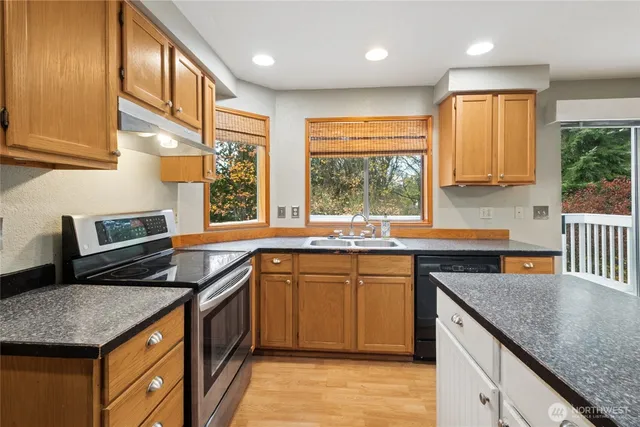 a kitchen with stainless steel appliances granite countertop sink stove top oven and cabinets