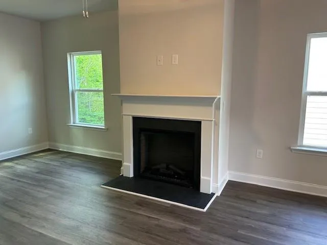 an empty room with wooden floor fireplace and windows