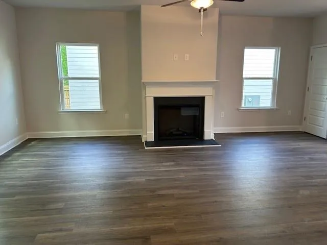 an empty room with wooden floor a fireplace and windows