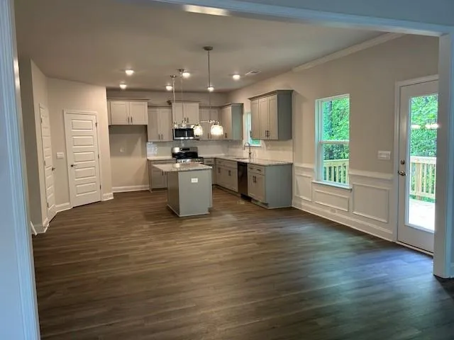 a view of kitchen with stainless steel appliances granite countertop a stove top oven a sink dishwasher a refrigerator and a dining table with wooden floor