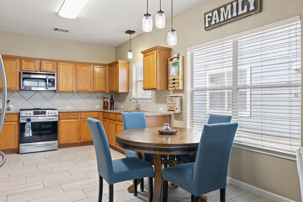 207 Rosedale Boulevard Georgetown, TX 78628 - Photo 13 of 30 Kitchen with appliances with stainless steel finishes, light stone counters, wood tiled floors, and hanging light fixtures