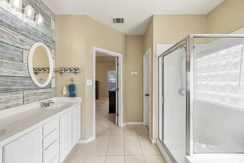 a spacious bathroom with a double vanity sink a mirror and a shower