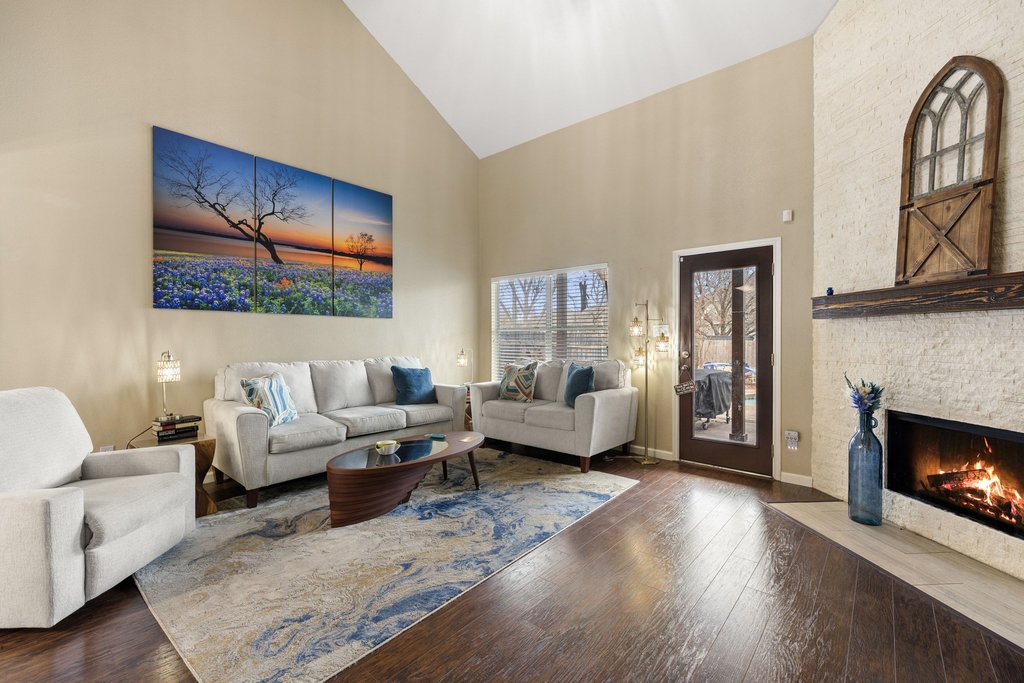 207 Rosedale Boulevard Georgetown, TX 78628 - Photo 4 of 30 A light-filled living room with soaring ceilings and a cozy fireplace, creating a welcoming space that feels both open and inviting.