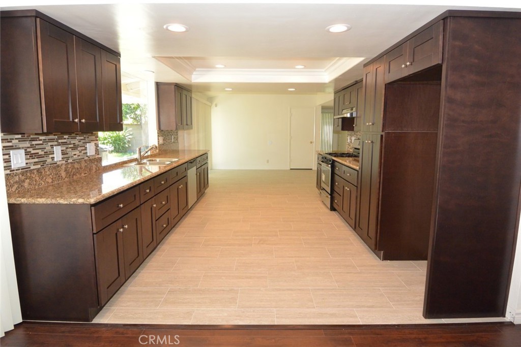 11392 Wallingsford Road Los Alamitos, CA 90720 - Photo 4 of 17 a large kitchen with kitchen island granite countertop a large counter top stainless steel appliances a sink and a refrigerator