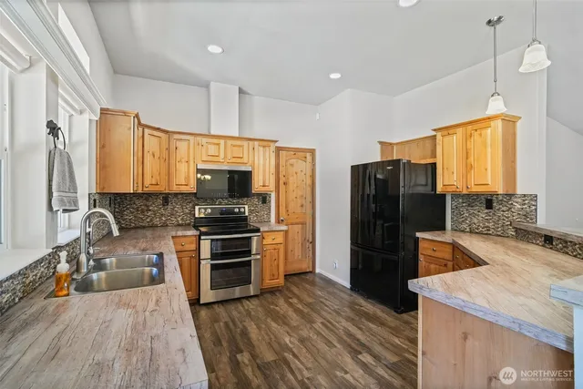 a kitchen with a refrigerator a sink and wooden floor