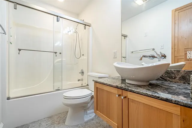 a bathroom with a granite countertop sink mirror vanity and toilet