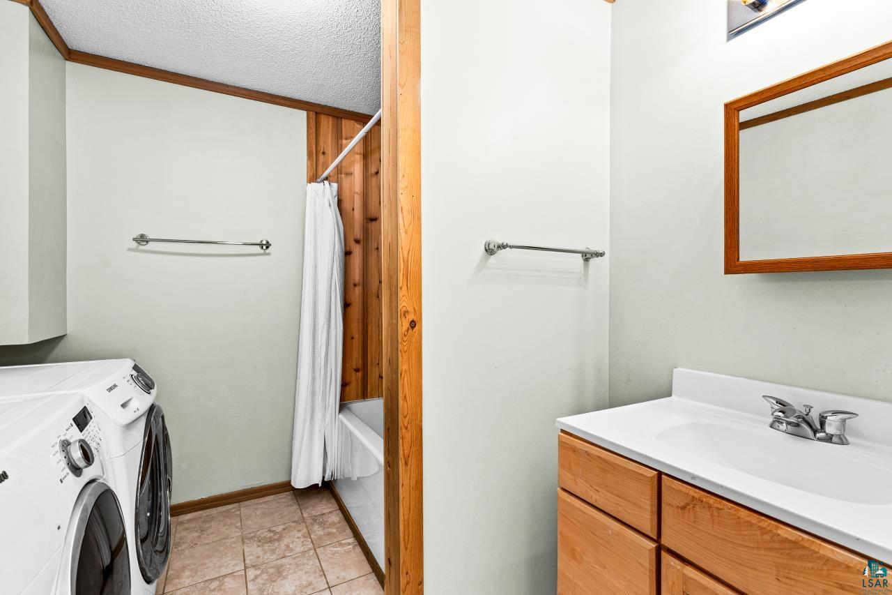 67 Snowshoe Trail Tofte, MN 55615 - Photo 38 of 42 Full bath with a textured ceiling, vanity, separate washer and dryer, light tile patterned flooring, and crown molding