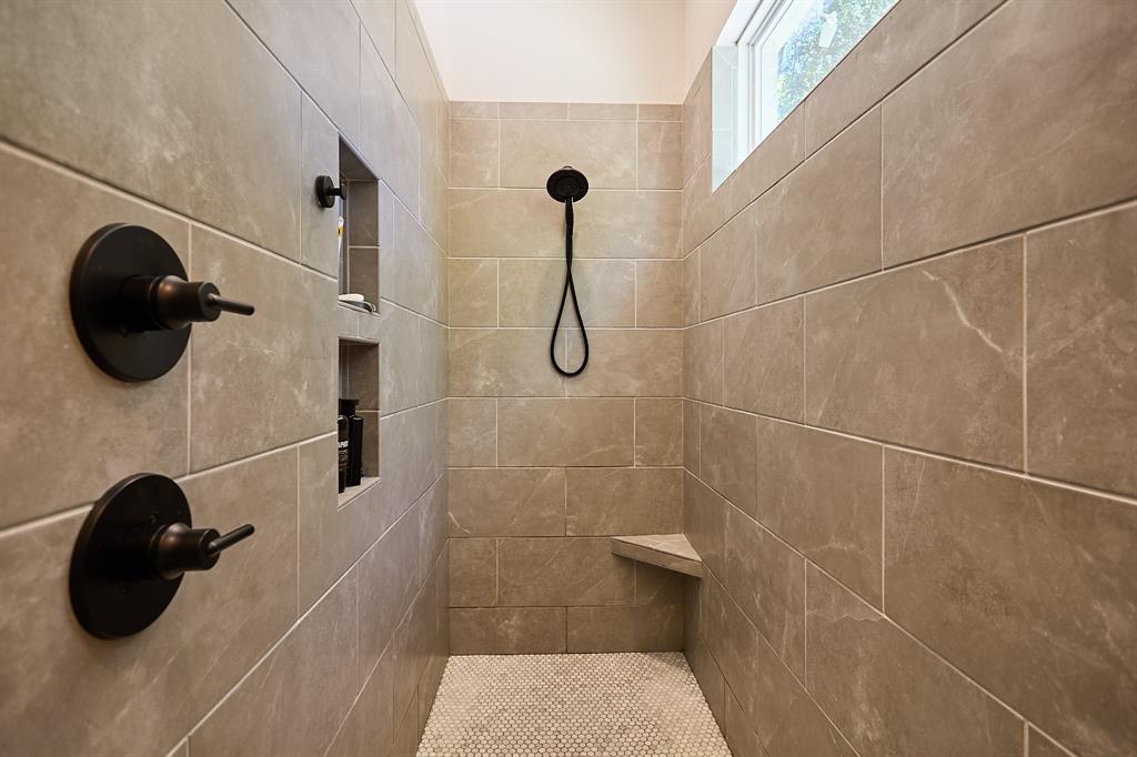 358 Glade Valley Road Azle, TX 76020 - Photo 15 of 35 Tiled shower enclosure featuring a fixed showerhead with a handheld sprayer, dual recessed niches, a built-in corner bench, and a privacy window