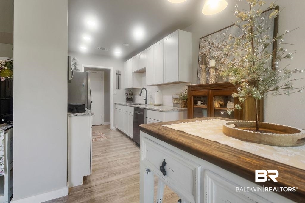 601 East Gate Circle Foley, AL 36535 - Photo 19 of 26 Kitchen featuring appliances with stainless steel finishes, light hardwood / wood-style floors, white cabinets, and sink