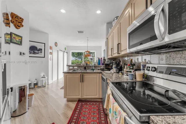 a kitchen with stainless steel appliances granite countertop a sink stove and cabinets