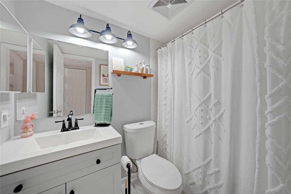 1591 Beach Road, Unit 202 Englewood, FL 34223 - Photo 21 of 46 a bathroom with a sink a toilet a mirror and shower curtain