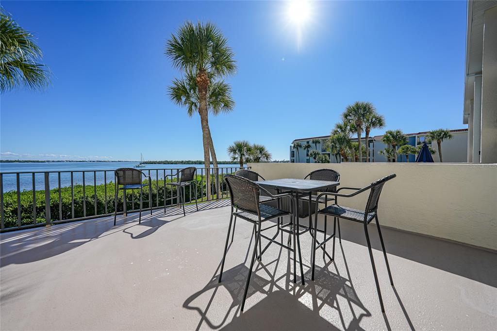1591 Beach Road, Unit 202 Englewood, FL 34223 - Photo 27 of 46 a patio with a table and chairs with potted plants