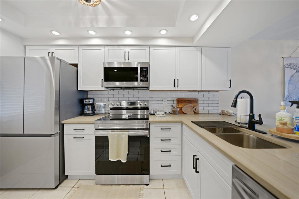 1591 Beach Road, Unit 202 Englewood, FL 34223 - Photo 9 of 46 a kitchen with stainless steel appliances granite countertop a refrigerator sink and white cabinets