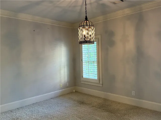 en empty room with windows and chandelier