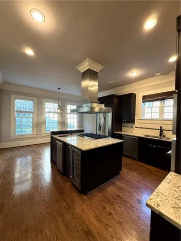 a large kitchen with stainless steel appliances granite countertop a large counter top and wooden floors