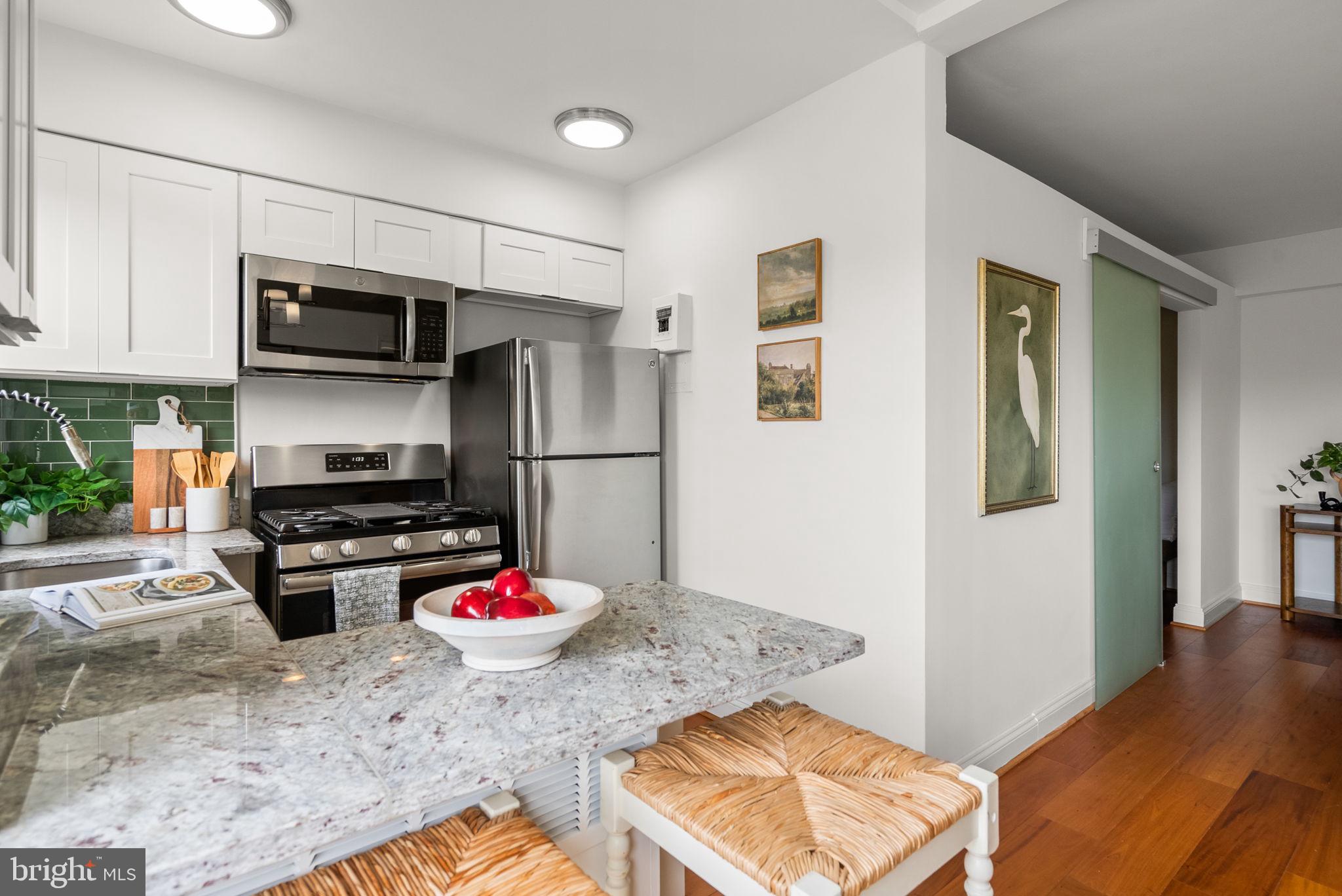 2500 Q Street Northwest, Unit 524 Washington, DC 20007 - Photo 24 of 50 a kitchen with stainless steel appliances granite countertop a stove refrigerator and microwave