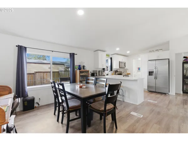 a kitchen with appliances a dining table chairs and white cabinets