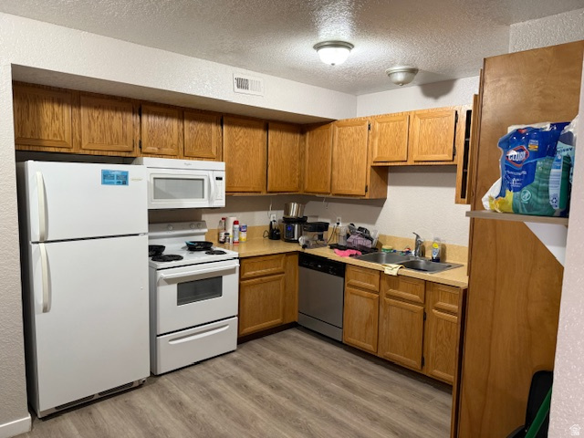 72 880 North, Unit 2 Provo, UT 84604 - Photo 4 of 9 Kitchen featuring wood-finish cabinetry, laminate countertops, a double basin stainless steel sink, and wood-finish flooring