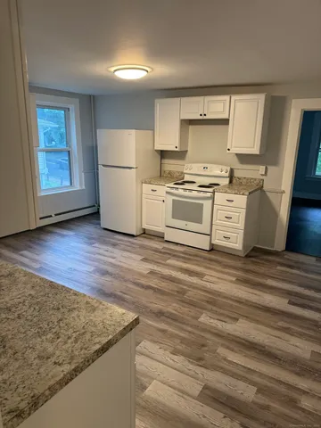 a kitchen with granite countertop a sink cabinets stainless steel appliances and a window