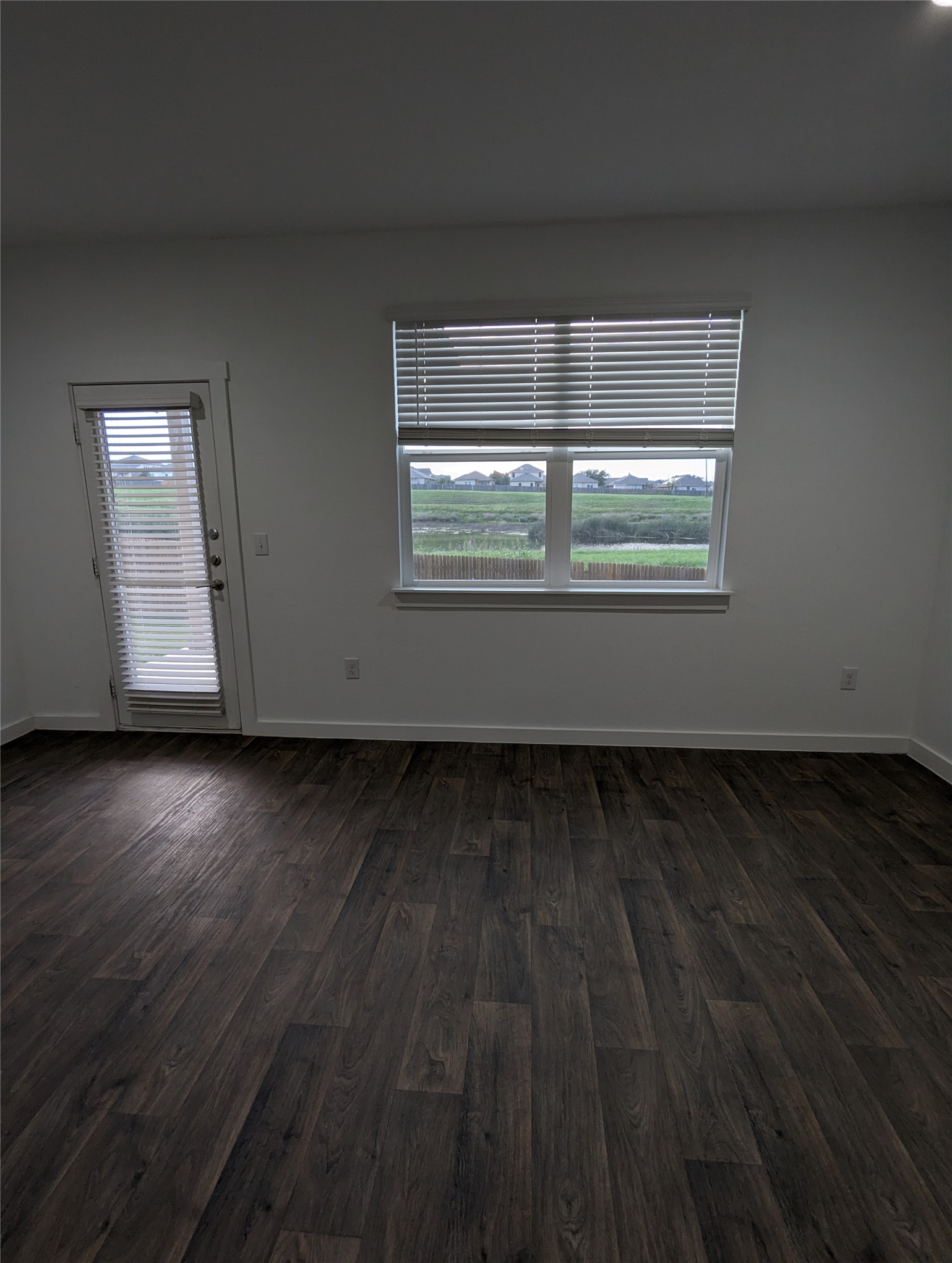 13804 Clerk Street Pflugerville, TX 78660 - Photo 4 of 14 a view of an empty room with wooden floor and a window