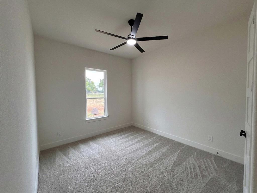 121 Cartwright Park Road Weatherford, TX 76087 - Photo 15 of 17 Spacious room featuring vaulted ceilings, a contemporary ceiling fan with integrated lighting, a single window providing natural illumination, and plush patterned carpeting